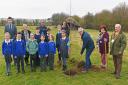 Phil Gillott, Gisleham parish council chairman, with councillors Linda Spendlove and Richard Dexter planting the tree watched by pupils and staff of Carlton Colville Primary School.