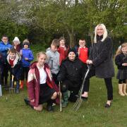 Executive head teacher Rae Aldous planting one of the Queen’s Green Canopy Trees at Grove Primary School watched by the eco-warriors.