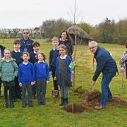 Phil Gillott, Gisleham parish council chairman, with councillors Linda Spendlove and Richard Dexter planting the tree watched by pupils and staff of Carlton Colville Primary School.