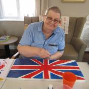 A resident at The Dell painting a Union Jack for the Coronation