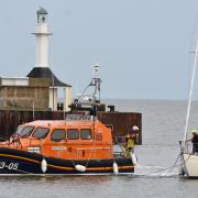 Lowestoft Lifeboat crew members connecting a tow line to bring the stranded 33ft yacht back into Lowestoft. Picture: Mick Howes