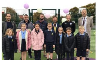 Multi gold medallist and world champion Giarnni Regini-Moran, and coach Pete Etherington, with staff and pupils at Woods Loke Primary School.